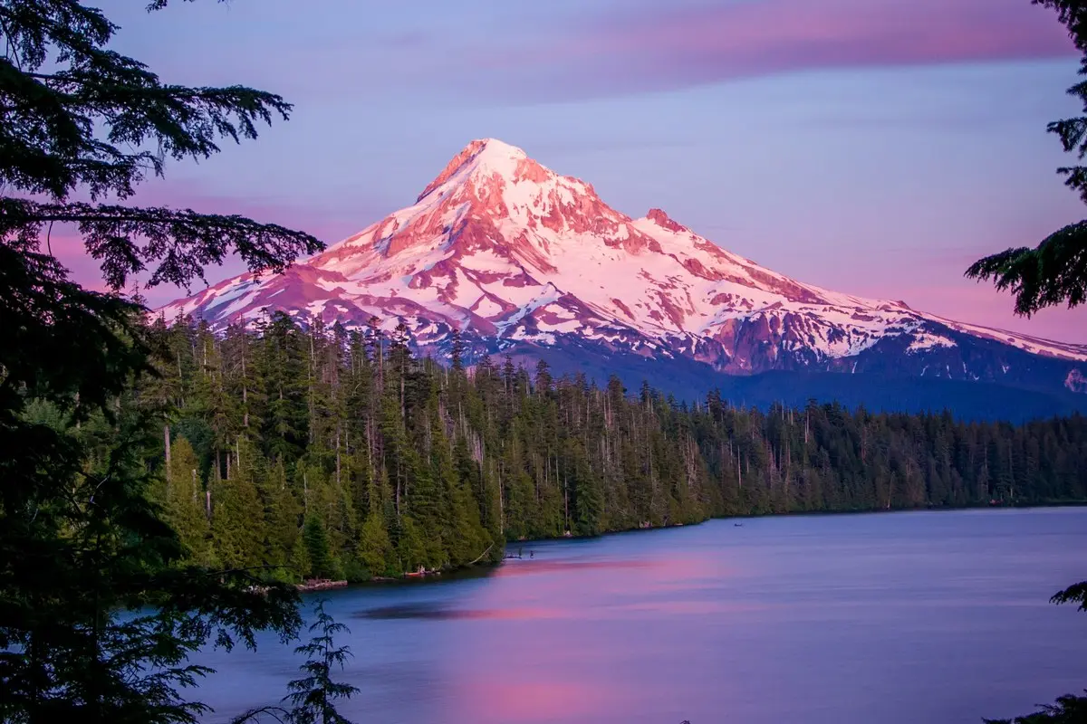 A stunning snow-capped mountain reflected in a pink-hued lake.